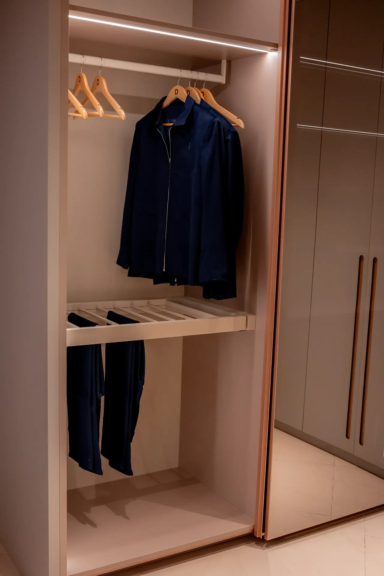 Módulo de closet com cabideiro, calceiro e portas espelhadas em acabamento acetinado.