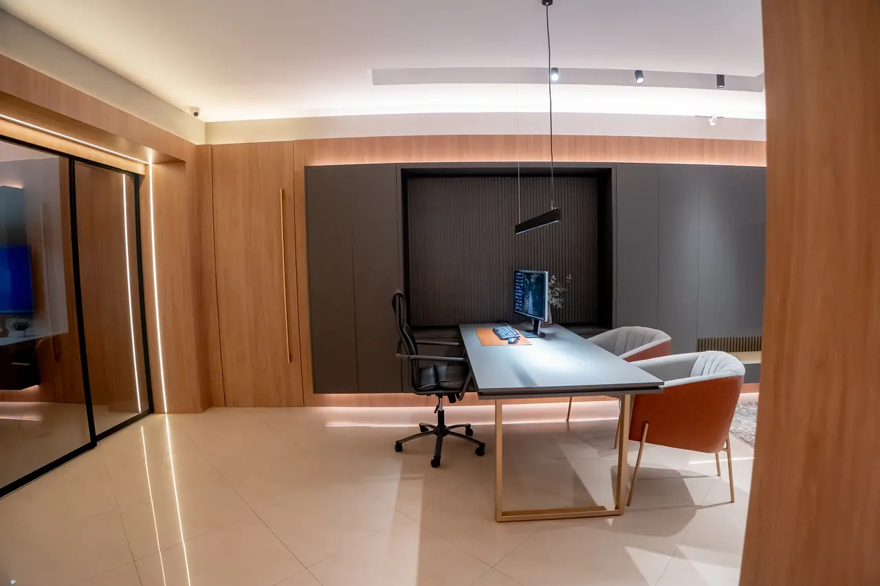 Escritório corporativo planejado com marcenaria em madeira, divisórias de vidro e mesa iluminada.