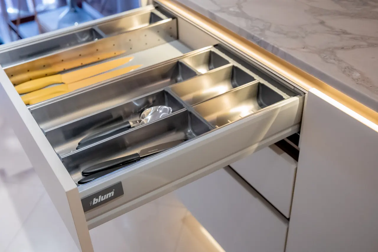 Gaveta de cozinha com organizador interno de talheres e iluminação integrada em móvel planejado sob medida.