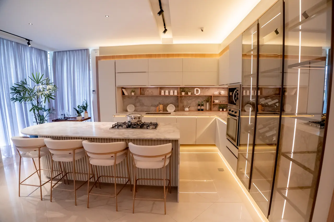 Cozinha planejada de alto padrão com ilha em mármore, banquetas e iluminação embutida na marcenaria, projeto ART CASA DALMÓBILE.